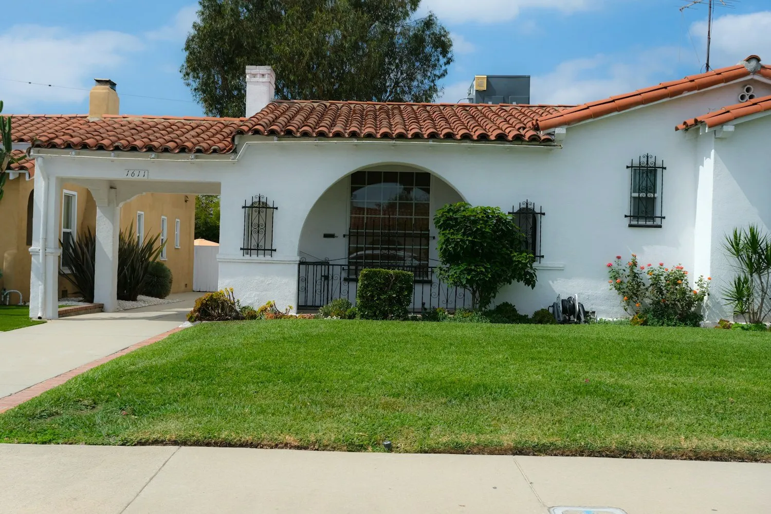 A single-story stucco home with a tiled roof on a quiet residential street.