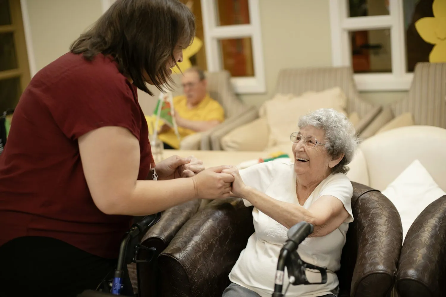 A caregiver steadying an older woman as she stands, her walker beside her.